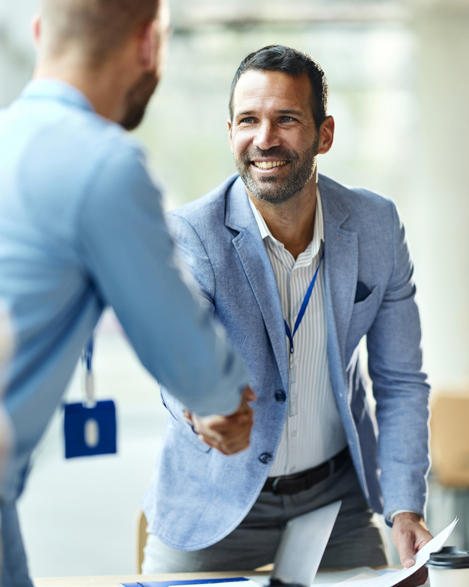 Happy businessman greeting his colleague on a meeting in the office.